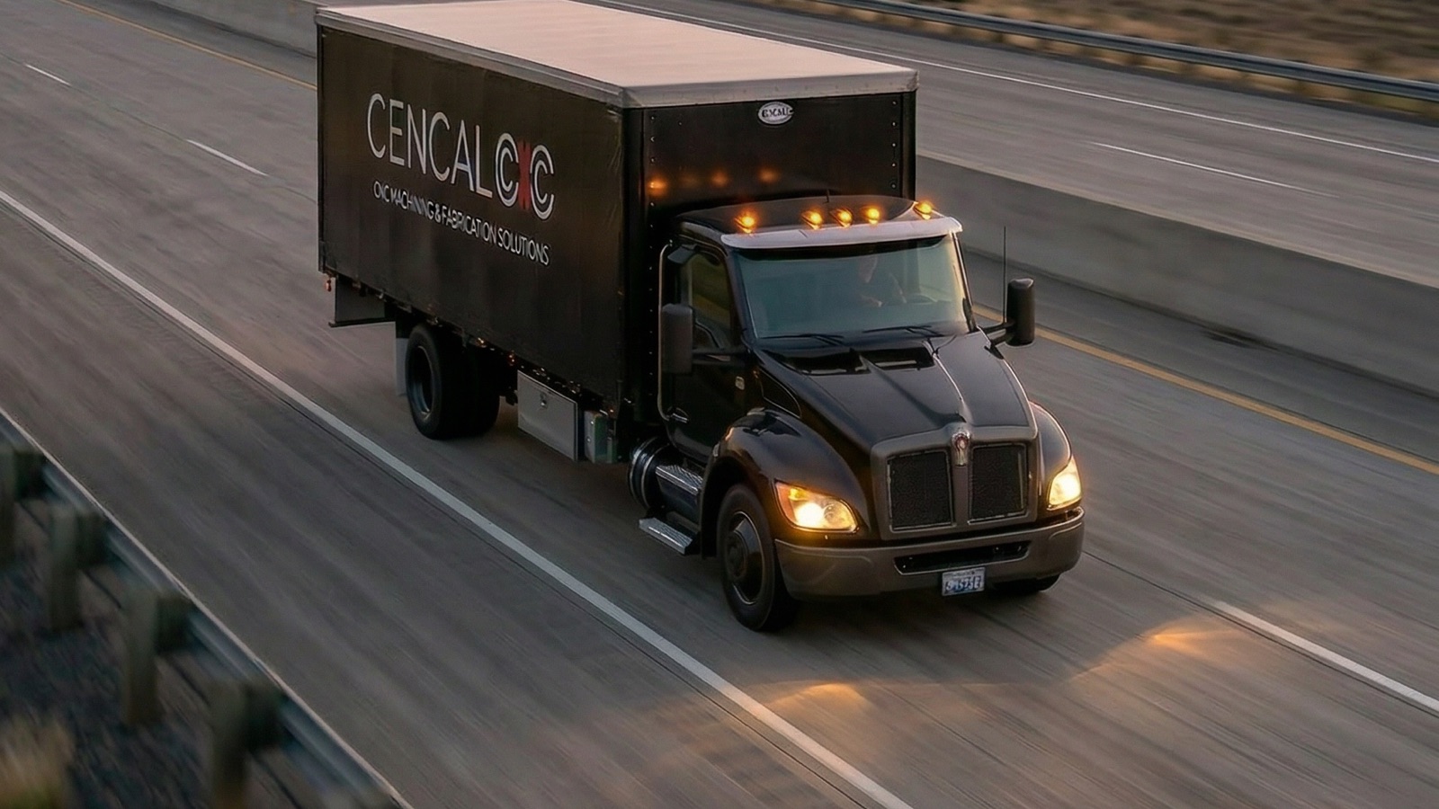 A CENCAL CNC delivery truck on a California highway, industrial plant on the horizon